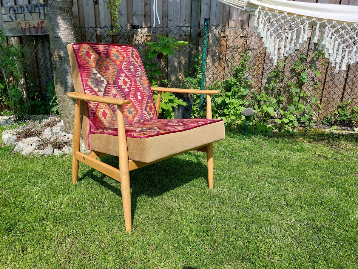 Vintage Sessel neu gepolstert im Boho-Stil, warme Farbtönte, helles Holzgestell, seitliche Ansicht im Garten