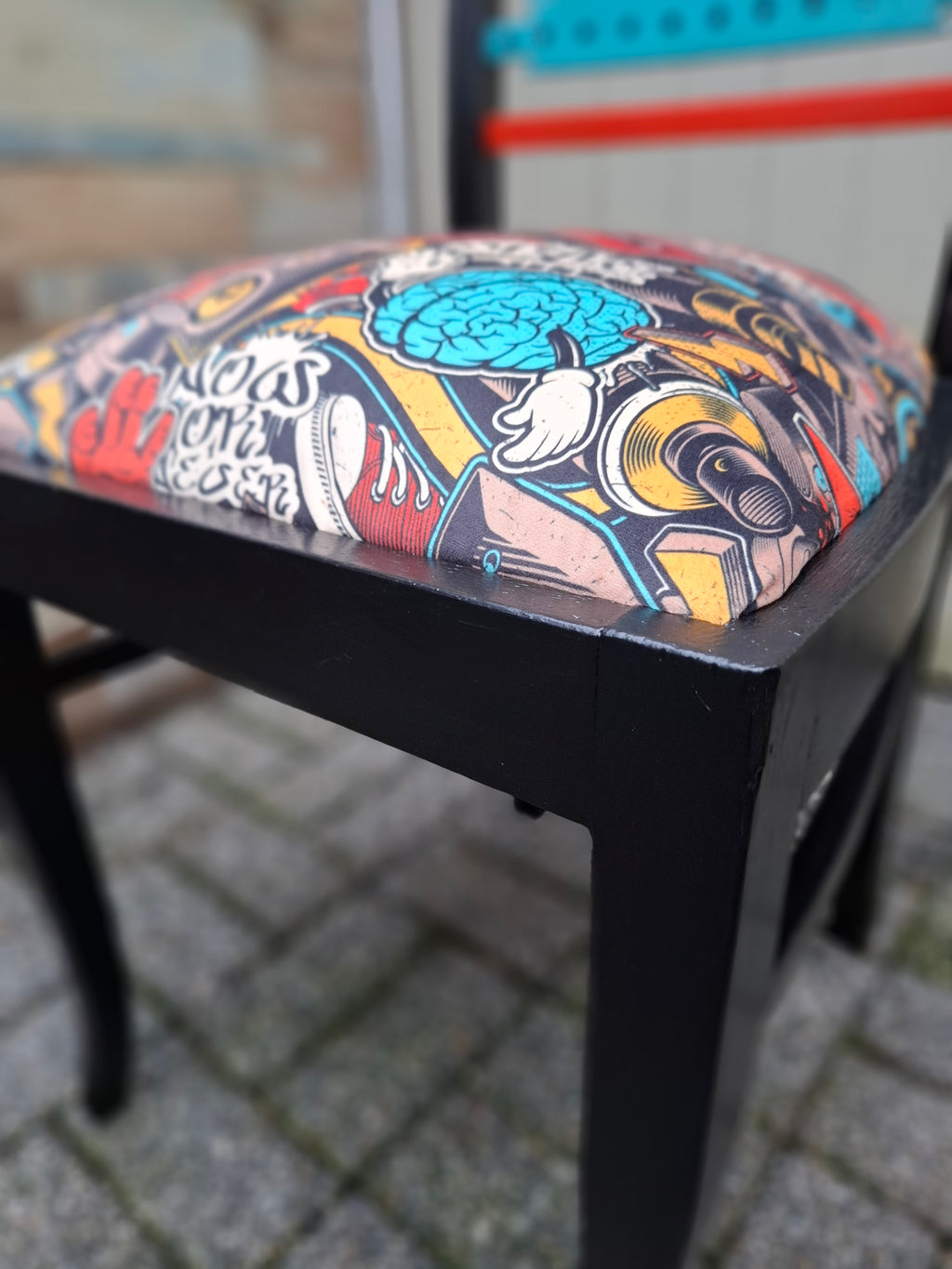 Alter Stuhl komplett aufgearbeitet, schwarzes Holzgestell mit gelben, roten und türkisen Akzenten auf der Rückenlehne, Sitz mit Veloursstoff bezogen mit einem Graffitimuster, Detailansicht Bein