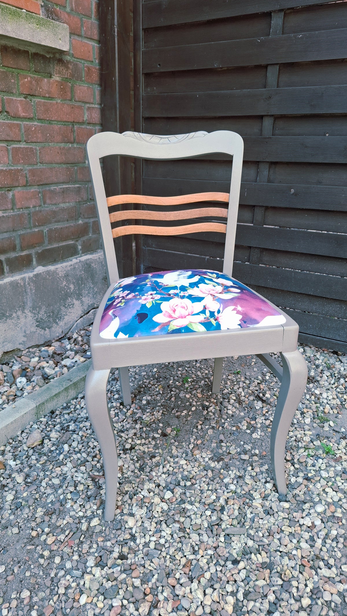 Alter Stuhl komplett aufgearbeitet, hellgraues Holzgestell mit naturbelassenen Holdetails auf der Rückenlehne, Sitz mit Veloursstoff bezogen mit Blumen und Kranichmuster, Frontalansicht 