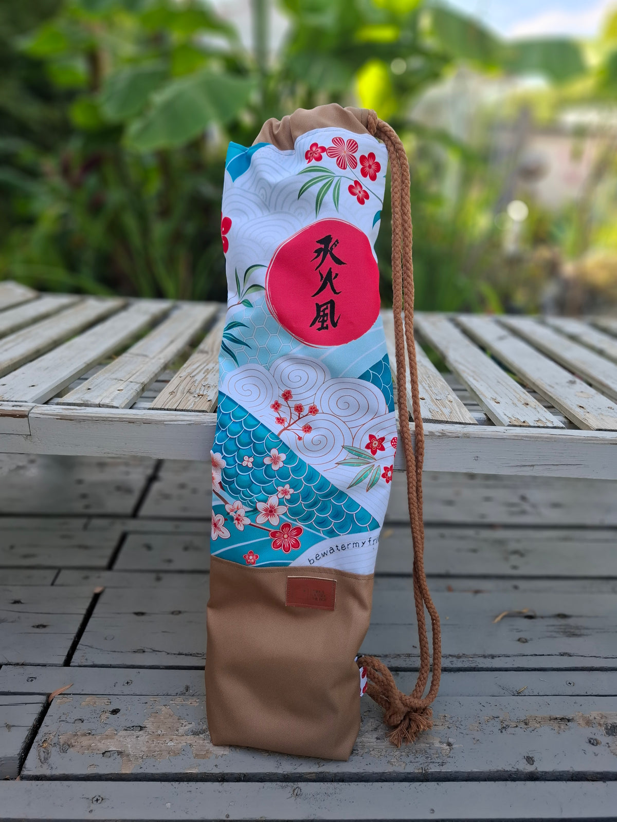 Hanzo Auguss Art Kellentasche für Saunakellen, oben buntes klassiches japanisches Muster mit den 3 Hanzo Kanji, unten Stoff in Karamell mit einem Things Outside The Box Lederetikett. Vorderansicht