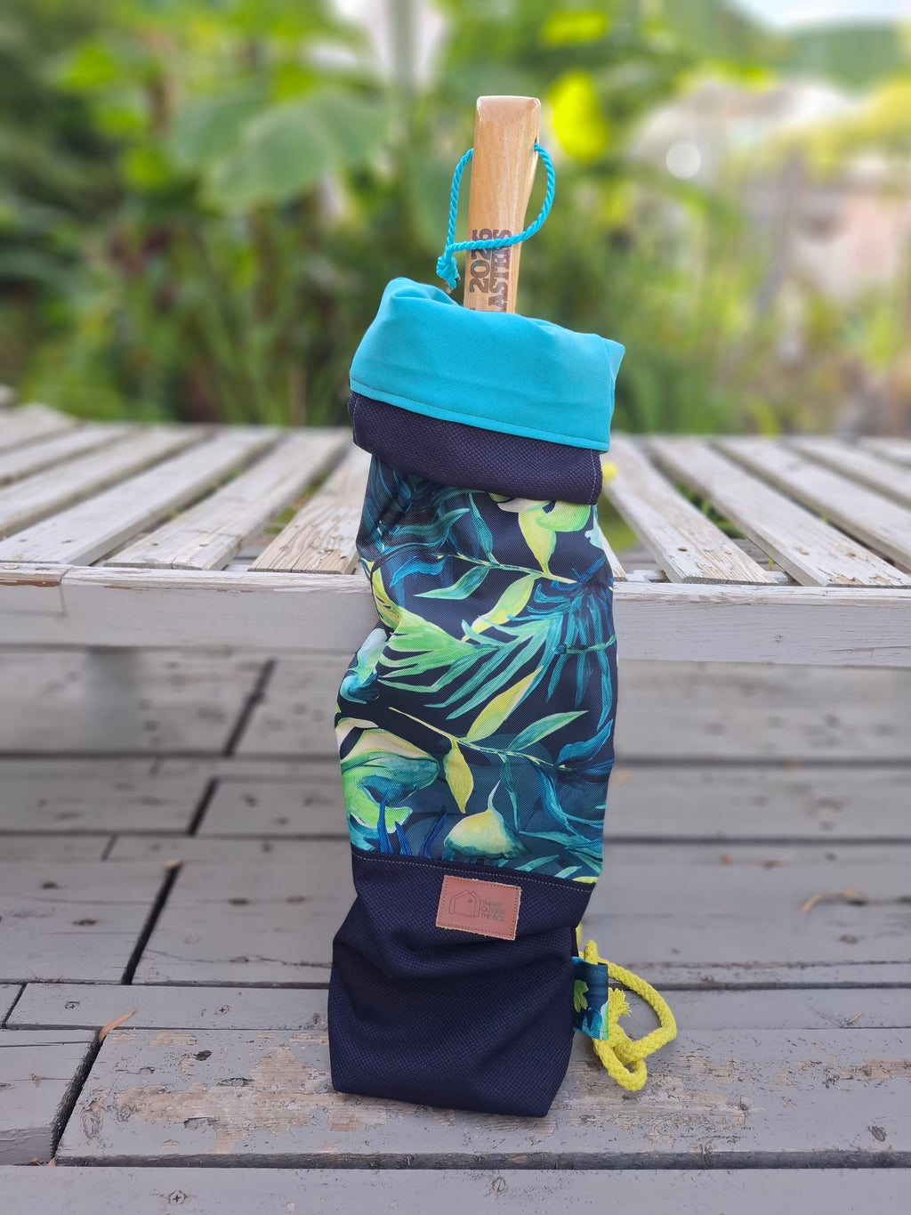 Kellentasche für Saunakellen, oben blau-grünes Muster mit Monstera und anderen Dschungelblättern, unten marineblauer Stoff , Ansicht blaues Innenfutter. Auf dem Bild ist auch eine Saunekelle in der Tasche sichtbar