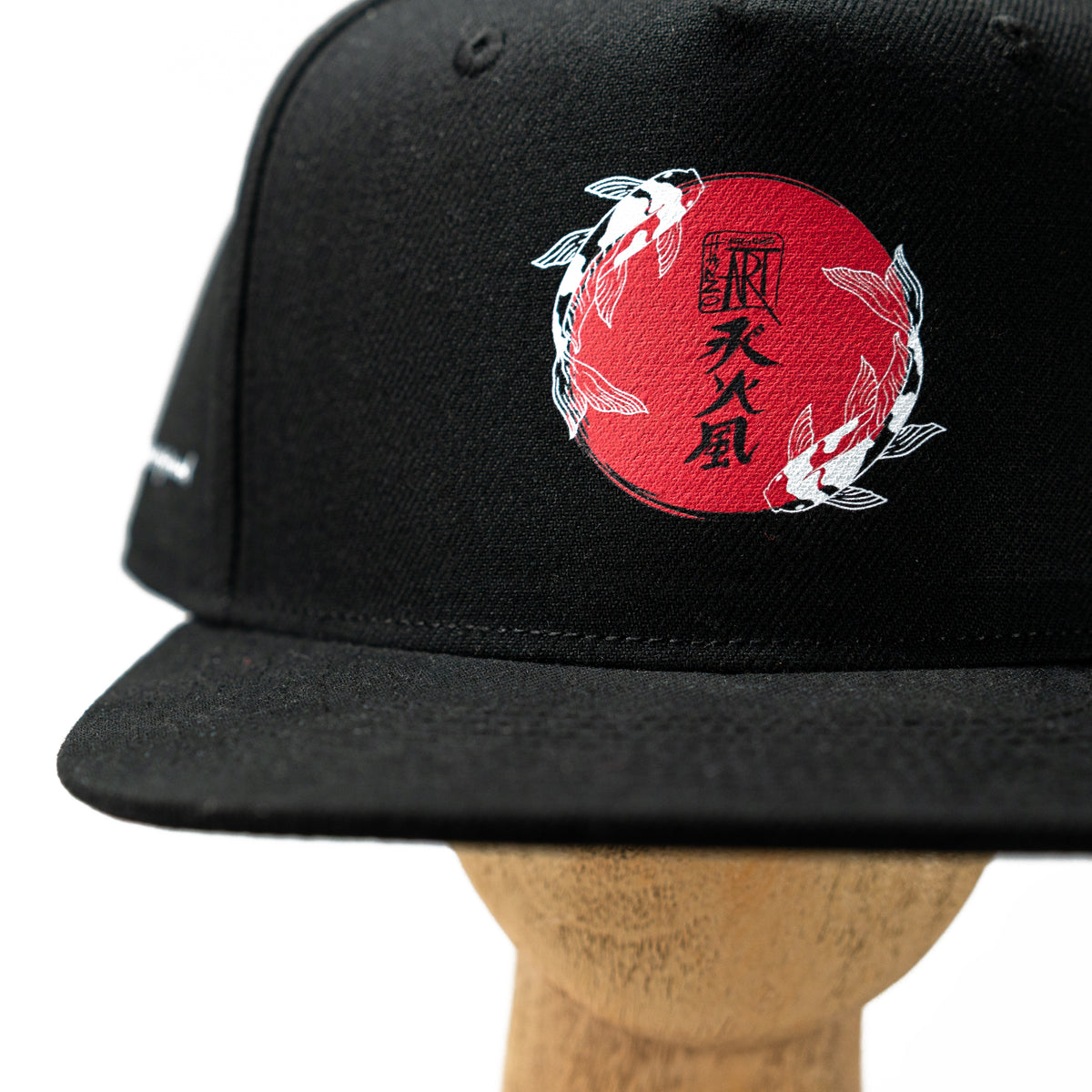 schwarzes Snapback Cap von Hanzo Aufguss Art, Detailansicht vorne Hanzo Aufguss Art Logo mit zwei Kois und den drei Kanji