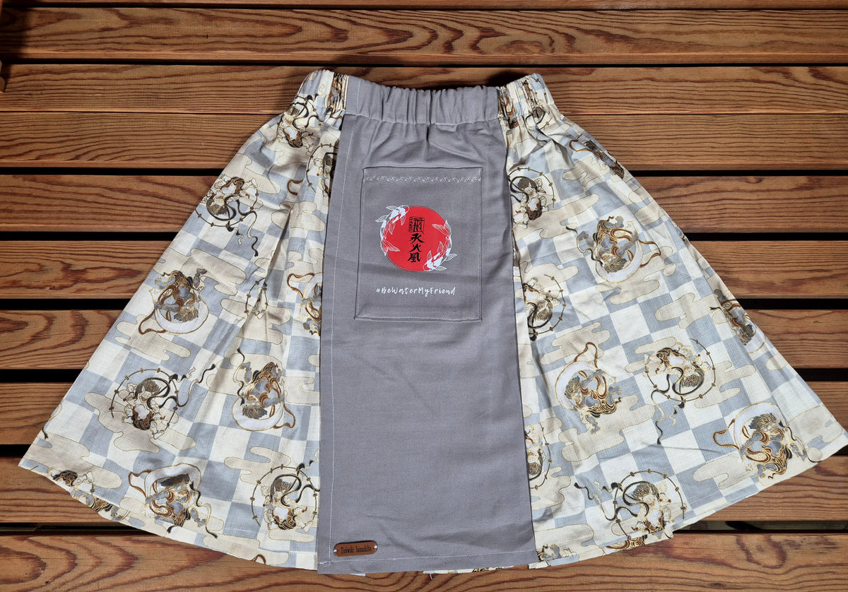 Hanzo Aufguss Art Kilt für Saunameister, japanisches Raijin&Fujin Muster beige-grau, vorne ein hellgrauer Streifen mit einer kleinen Tasche drauf, auf der Tasche das Hanzo Logo, unten ein kleines Logoetikett von Tiröwiki, Vorderansicht Gesamtansicht