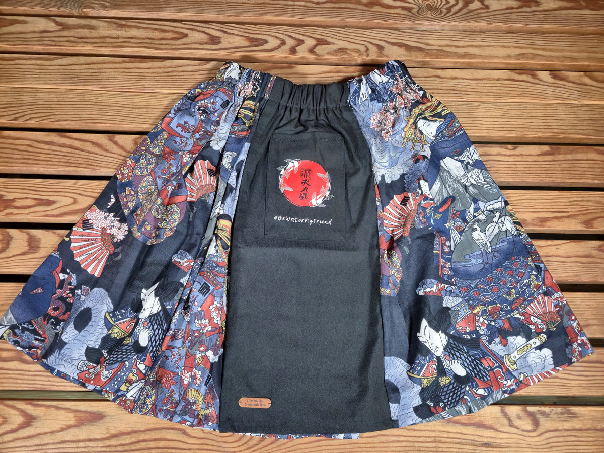 Hanzo Aufguss Art Kilt für Saunameister, japanisches Muster mit Samuraj, Kranichen und Fächern, vorne ein schwarzer Streifen mit einer kleinen Tasche drauf, auf der Tasche das Hanzo Logo, unten ein kleines Logoetikett von Tiröwiki, Vorderansicht Gesamtansicht