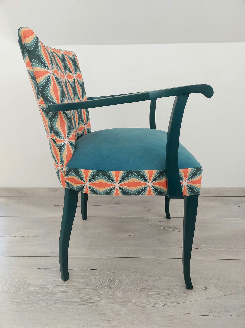 Bunter Vintagestuhl mit Armlehnen, Sitz blau gepolstert, Retro-Muster blau orange, dunkelblaues Holzgestell, Seitenansicht rechts