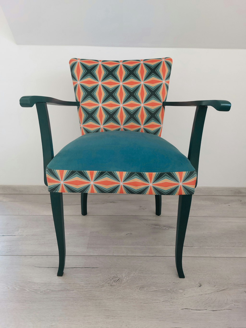 Bunter Vintagestuhl mit Armlehnen, Sitz blau gepolstert, Retro-Muster blau orange, dunkelblaues Holzgestell, Frontalansicht